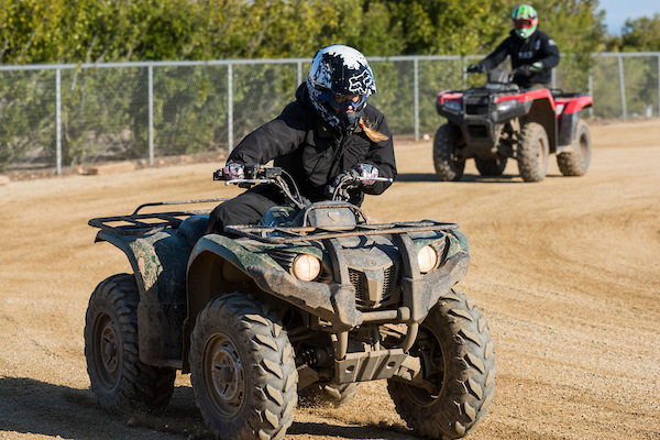 Riders on ATVs on a dirt trail.